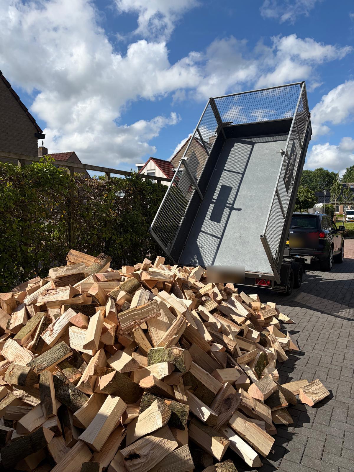 Vers gekloofd haardhout wordt gestort vanaf de aanhanger
